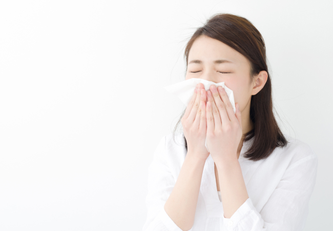 女性が鼻をかんでいるイメージ